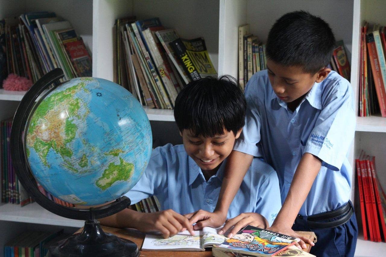 Peserta didik Sekolah Rahai belajar dengan globe di perpustakaan